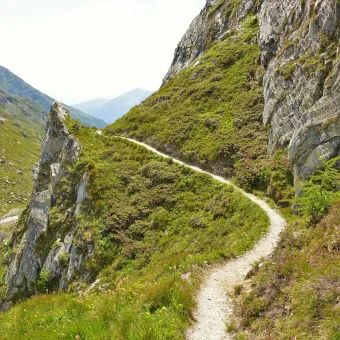 Schmaler Bergwanderweg durch felsdurchsetztes Gelände.